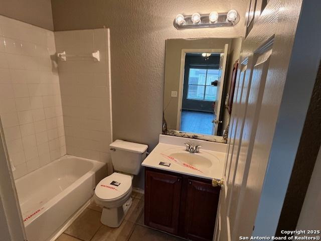 full bathroom with vanity, tiled shower / bath, tile patterned floors, and toilet