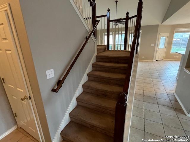 stairs with tile patterned floors and vaulted ceiling