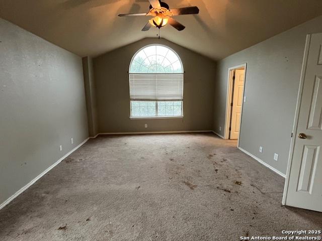 empty room featuring vaulted ceiling, light colored carpet, and ceiling fan