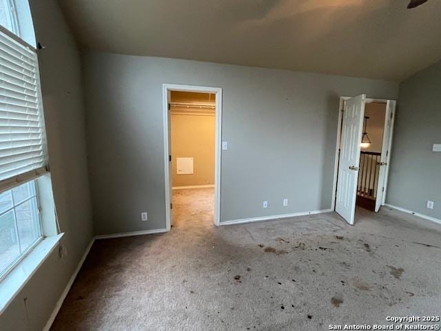 unfurnished bedroom with light carpet and a spacious closet