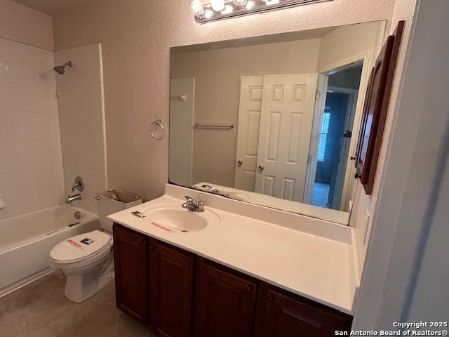 full bathroom featuring tiled shower / bath combo, vanity, and toilet