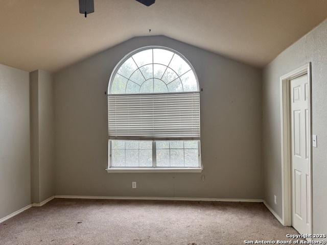 carpeted spare room featuring lofted ceiling and ceiling fan