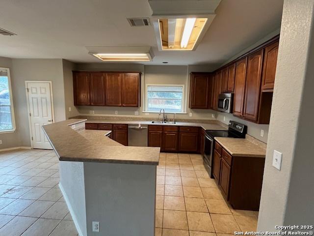 kitchen with stainless steel appliances, sink, and light tile patterned floors