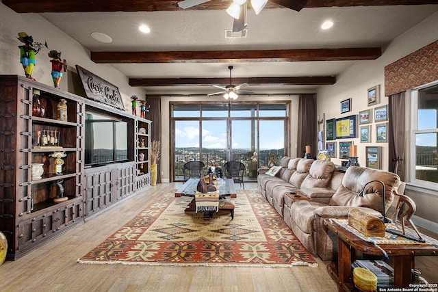 living room with beam ceiling, light wood-type flooring, a textured ceiling, and ceiling fan