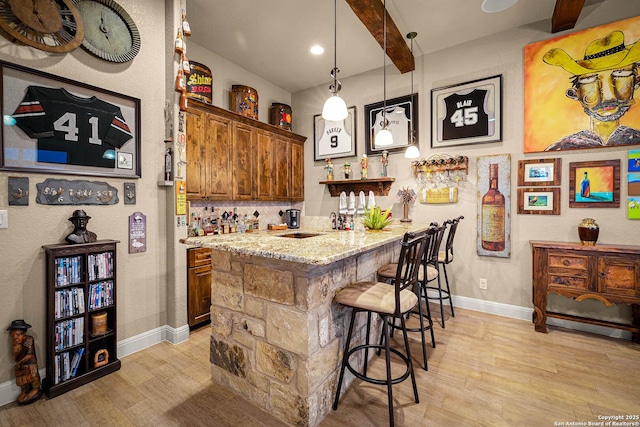 bar featuring light stone counters, beam ceiling, decorative light fixtures, and light wood-type flooring