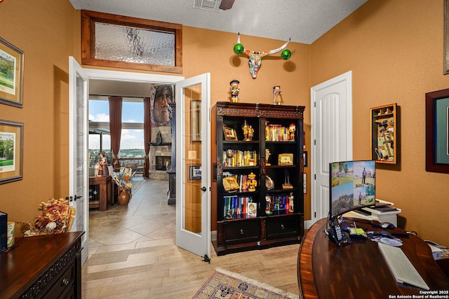 office featuring french doors, light hardwood / wood-style floors, and a textured ceiling