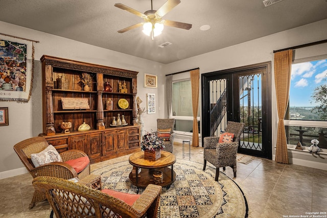 sitting room with a textured ceiling, tile patterned floors, and ceiling fan