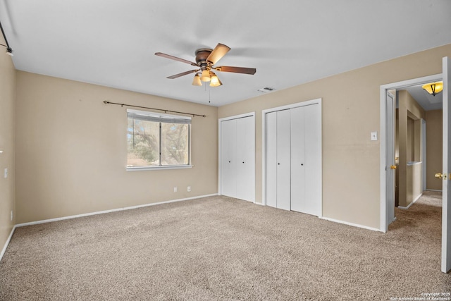 unfurnished bedroom featuring multiple closets, ceiling fan, and carpet