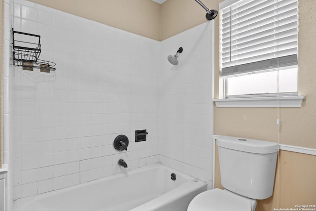 bathroom featuring tiled shower / bath combo and toilet