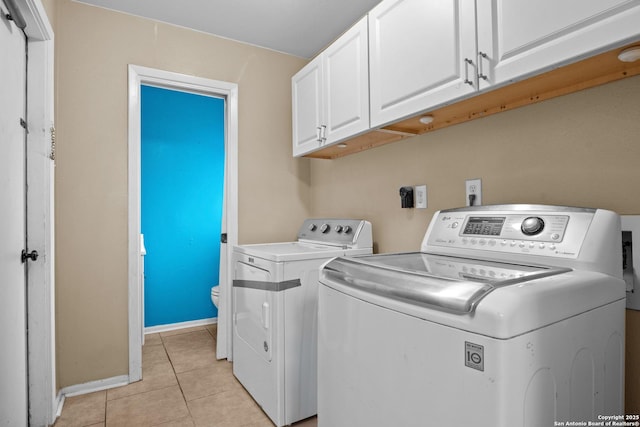 clothes washing area with cabinets, independent washer and dryer, and light tile patterned flooring