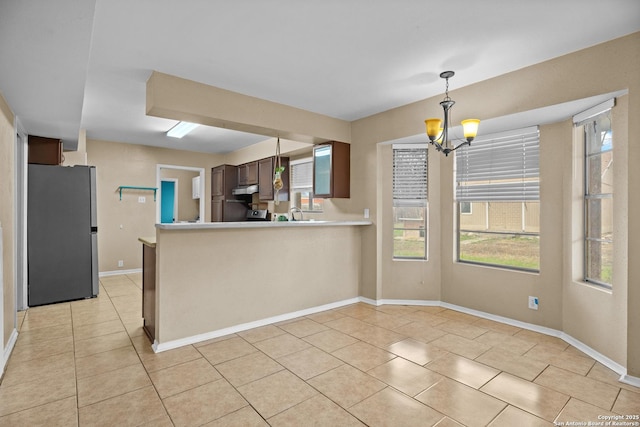 kitchen featuring an inviting chandelier, hanging light fixtures, light tile patterned floors, stainless steel fridge, and kitchen peninsula