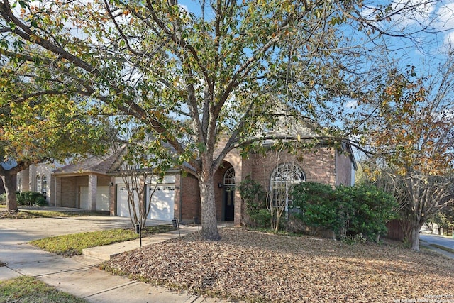 obstructed view of property featuring a garage, concrete driveway, and brick siding