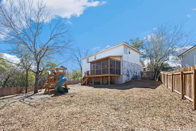 back of property with a sunroom, a playground, and a fenced backyard