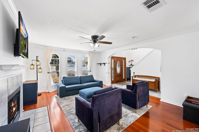 living room featuring light wood-style floors, a fireplace, visible vents, and arched walkways