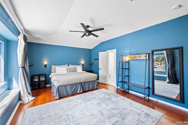 bedroom with a ceiling fan, vaulted ceiling, and wood finished floors