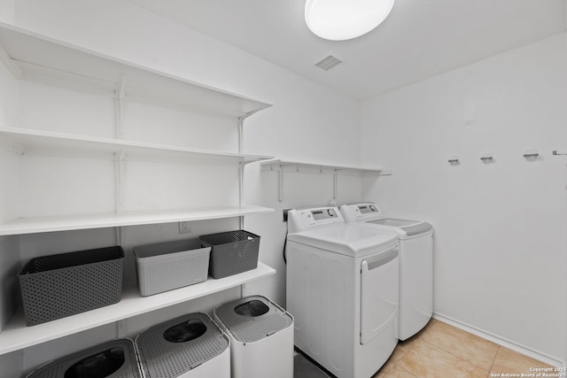 laundry area featuring laundry area, visible vents, washing machine and clothes dryer, and light tile patterned floors