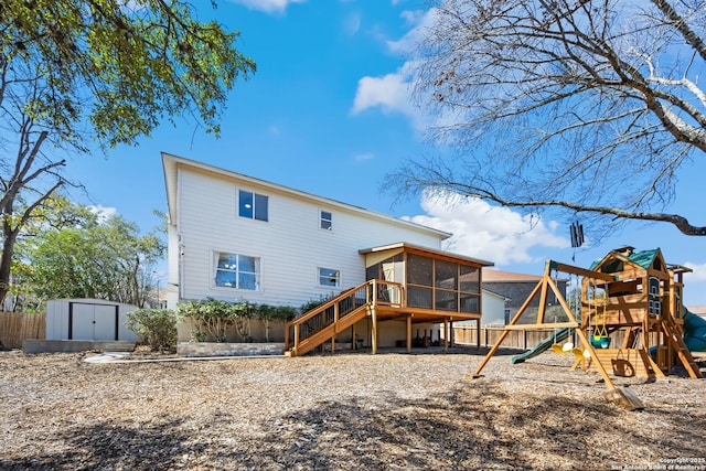 back of property featuring a playground, a storage shed, an outdoor structure, fence, and a sunroom