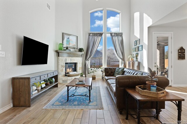 living room featuring plenty of natural light, a stone fireplace, and wood finished floors