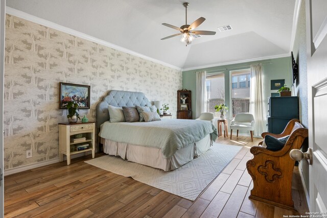 bedroom featuring visible vents, wallpapered walls, lofted ceiling, and wood finished floors