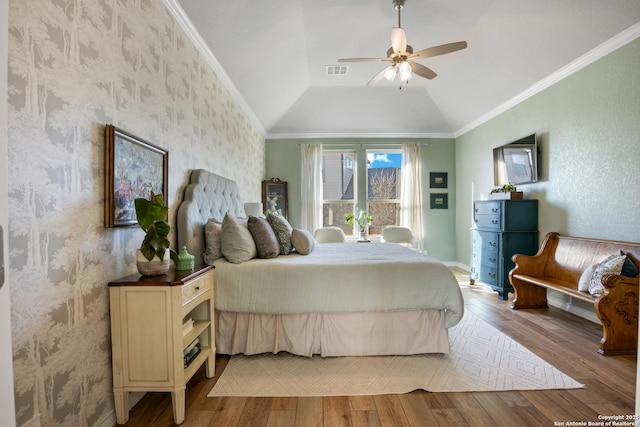 bedroom with vaulted ceiling, crown molding, visible vents, and wood finished floors