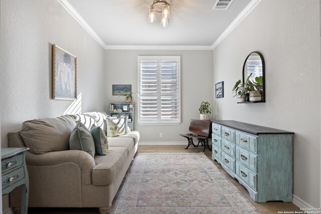 living area with visible vents, baseboards, light wood-style floors, and ornamental molding