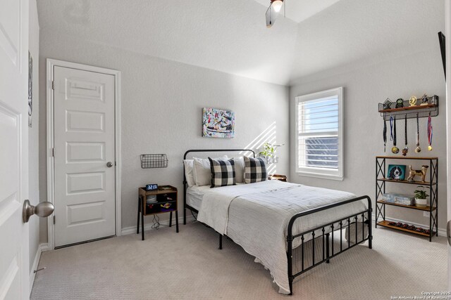 bedroom featuring vaulted ceiling, light colored carpet, and baseboards