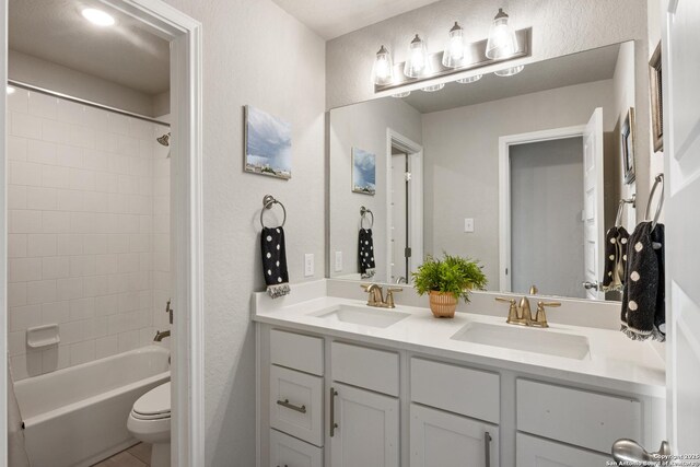 bathroom with a sink, toilet,  shower combination, and double vanity