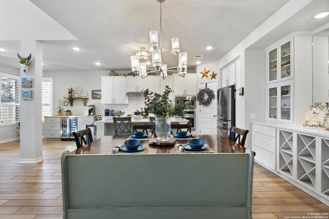 dining space featuring visible vents, an inviting chandelier, light wood-style flooring, recessed lighting, and wine cooler