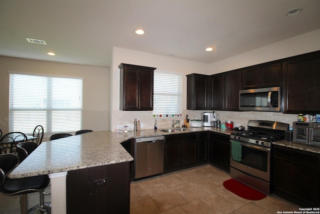 kitchen featuring sink, a kitchen breakfast bar, kitchen peninsula, and appliances with stainless steel finishes