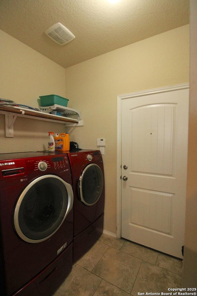 laundry area featuring light tile patterned flooring, washer and dryer, and a textured ceiling