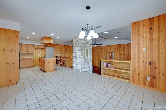 kitchen featuring decorative light fixtures, vaulted ceiling, wooden walls, a kitchen island, and a notable chandelier