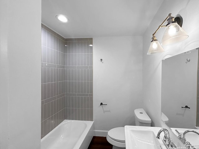 full bathroom featuring wood-type flooring, toilet, tiled shower / bath combo, and sink