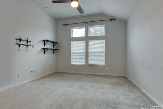 empty room with vaulted ceiling, light colored carpet, and ceiling fan