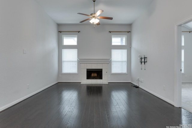 unfurnished living room featuring a tile fireplace, dark hardwood / wood-style floors, and ceiling fan