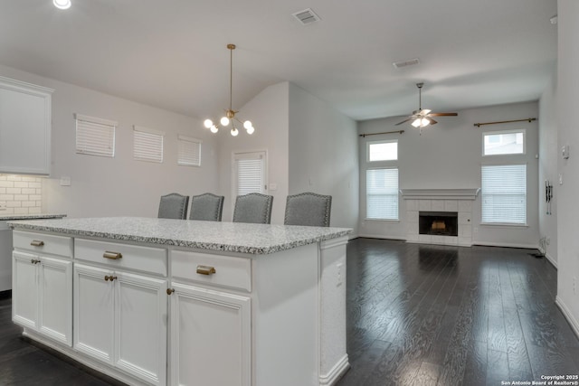 kitchen featuring a tile fireplace, white cabinets, dark hardwood / wood-style flooring, and decorative light fixtures