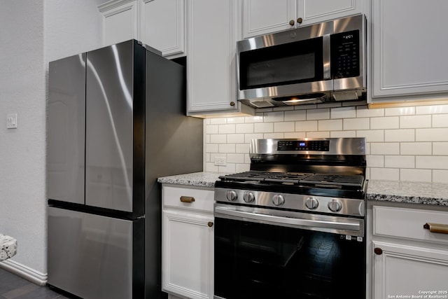 kitchen with stainless steel appliances, tasteful backsplash, light stone countertops, and white cabinets