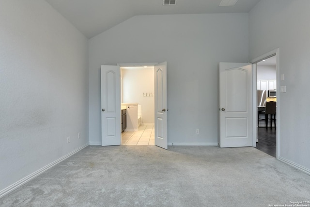 unfurnished bedroom featuring ensuite bathroom, vaulted ceiling, and light carpet