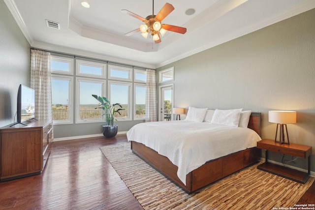 bedroom featuring ornamental molding, dark wood-type flooring, ceiling fan, and a tray ceiling