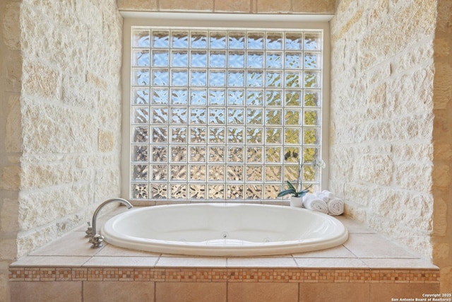 bathroom with a healthy amount of sunlight and a relaxing tiled tub