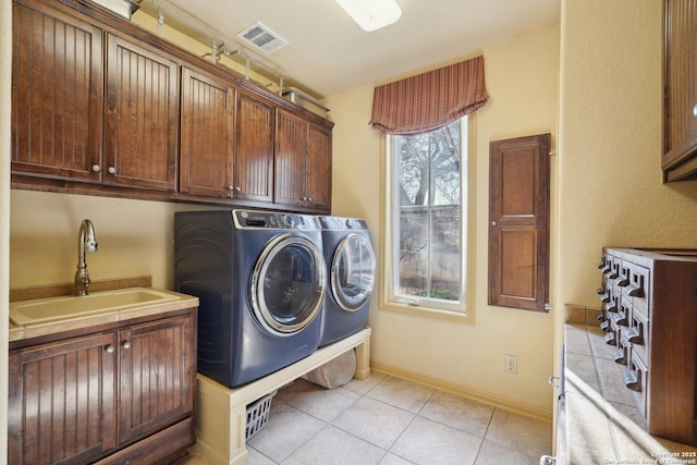 laundry room featuring sink, light tile patterned floors, cabinets, and independent washer and dryer