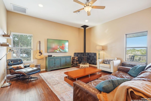 living room with hardwood / wood-style flooring, plenty of natural light, ceiling fan, and a wood stove