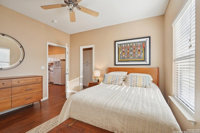 bedroom featuring white refrigerator, ceiling fan, dark hardwood / wood-style floors, and multiple windows