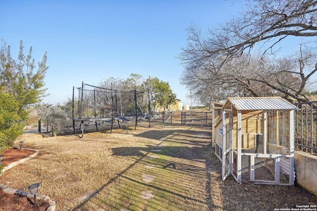 view of yard featuring a trampoline and an outbuilding