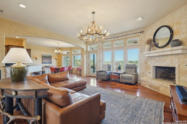 living room with a notable chandelier, crown molding, dark wood-type flooring, and a fireplace