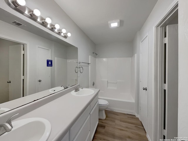 full bathroom with wood-type flooring, shower / washtub combination, vanity, and toilet