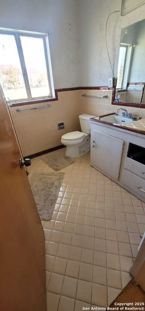 bathroom featuring tile patterned flooring, vanity, tile walls, and toilet