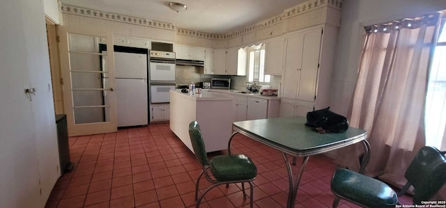 kitchen with white cabinetry, white appliances, and tile patterned flooring