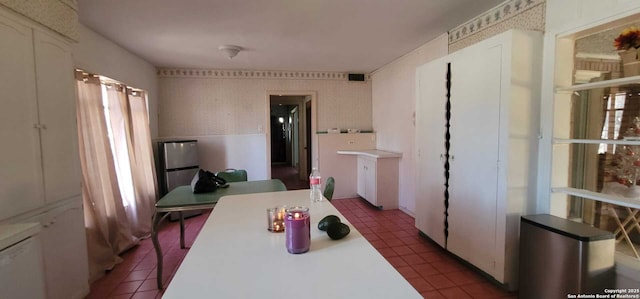 kitchen featuring white cabinetry, stainless steel fridge, and dark tile patterned floors