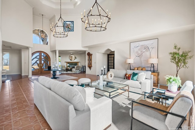 living room featuring a towering ceiling, ornamental molding, and ornate columns