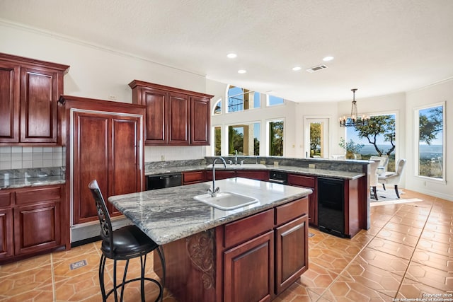 kitchen featuring a breakfast bar, decorative light fixtures, an island with sink, sink, and backsplash